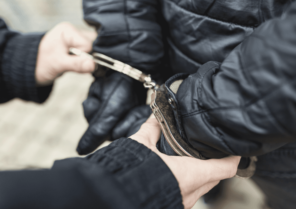 Close up of hands attaching handcuffs to gloved hands