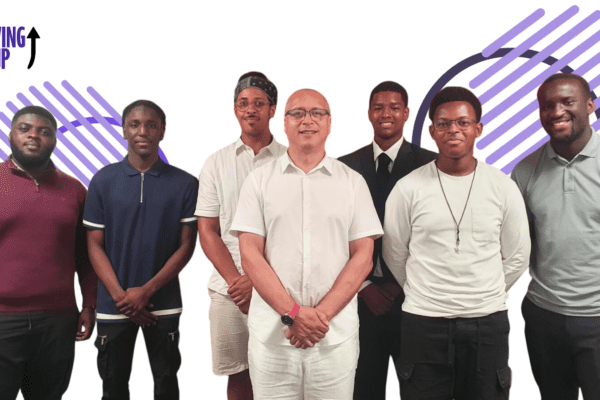 A group of seven smiling men stands in a line against a background featuring purple diagonal stripe patterns and the "MOVING ON UP" logo.