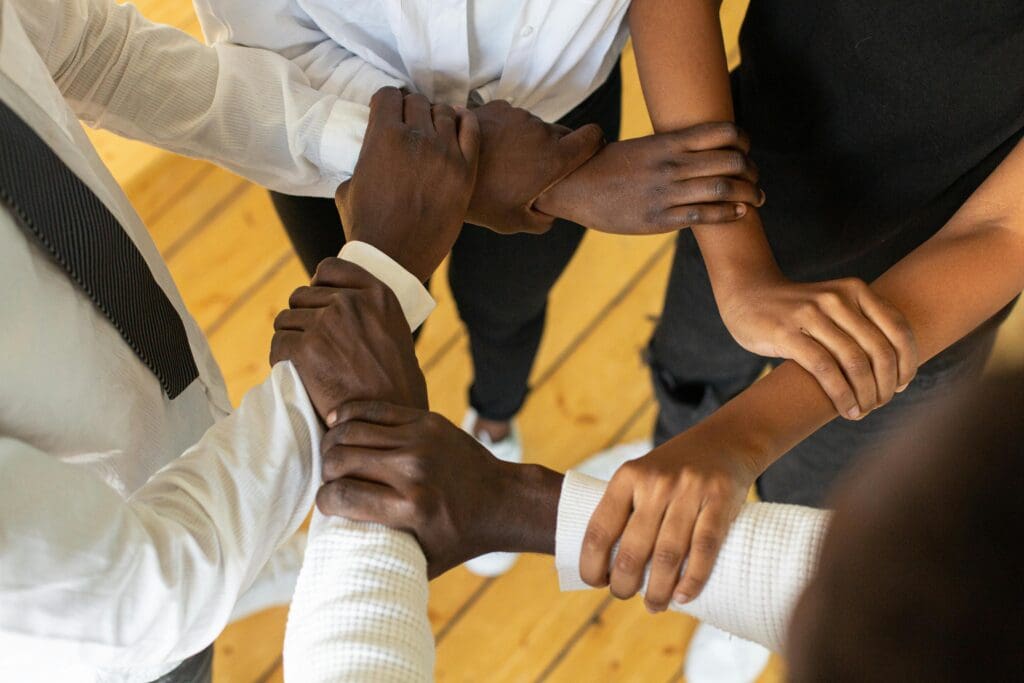 Close-up of diverse hands joined together to symbolise unity and teamwork.