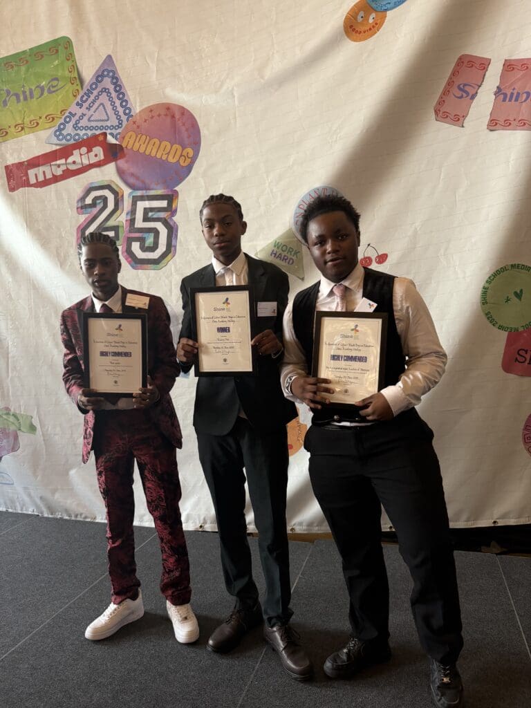 Photo of three Black boys wearing suits and holding up their Shine Media awards.