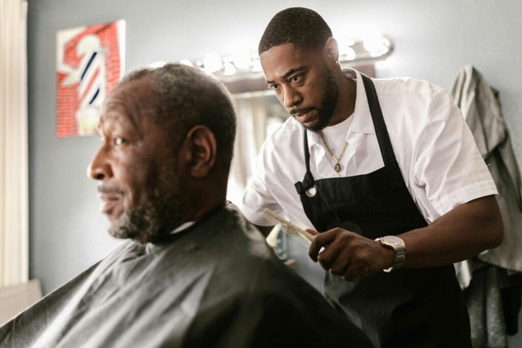 A focused barber performs a haircut on an elderly client in a contemporary barbershop setting.