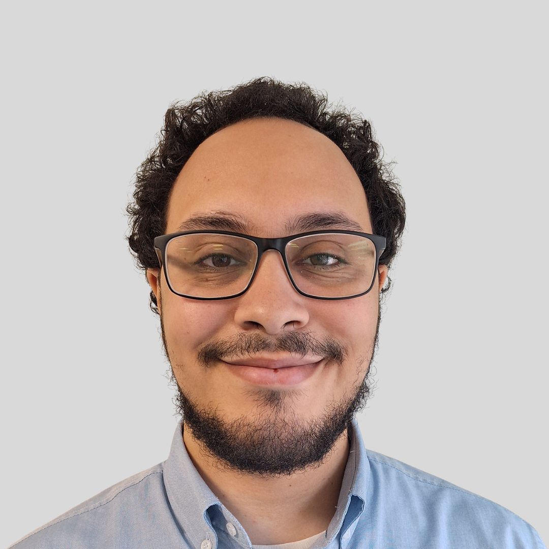 Headshot of man with beard and glasses smiling at the camera 