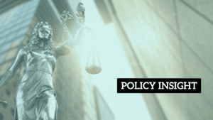 A statue of Lady Justice holds scales in front of buildings, with a bright light flare and the text "POLICY INSIGHT" in a black box.
