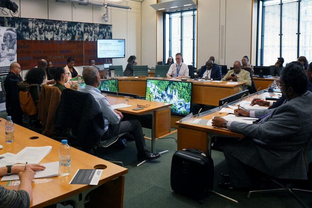People in a board meeting all in formal attire, discussing Windrush policy