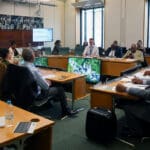 People in a board meeting all in formal attire, discussing Windrush policy