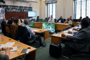People in a board meeting all in formal attire, discussing Windrush policy