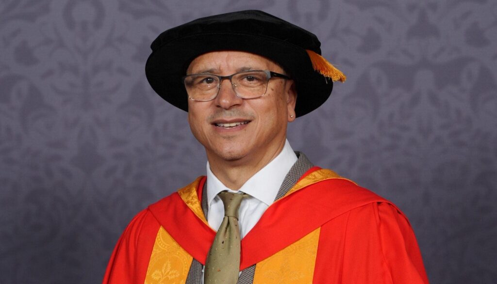 Dr Jeremy Crook OBE clutching a scroll.