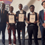 A group of five men, including three students holding award certificates, stand together for a photo in front of a colorful "Shine School Media Awards" backdrop.